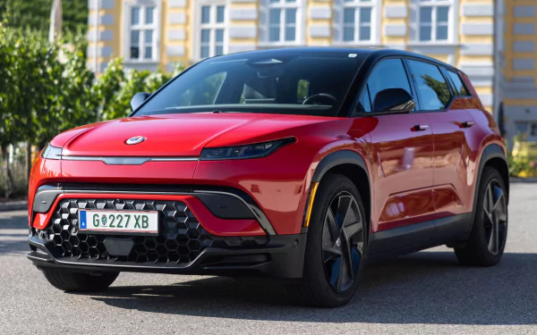 HD wallpaper of a red Fisker Ocean electric car parked with a building in the background.