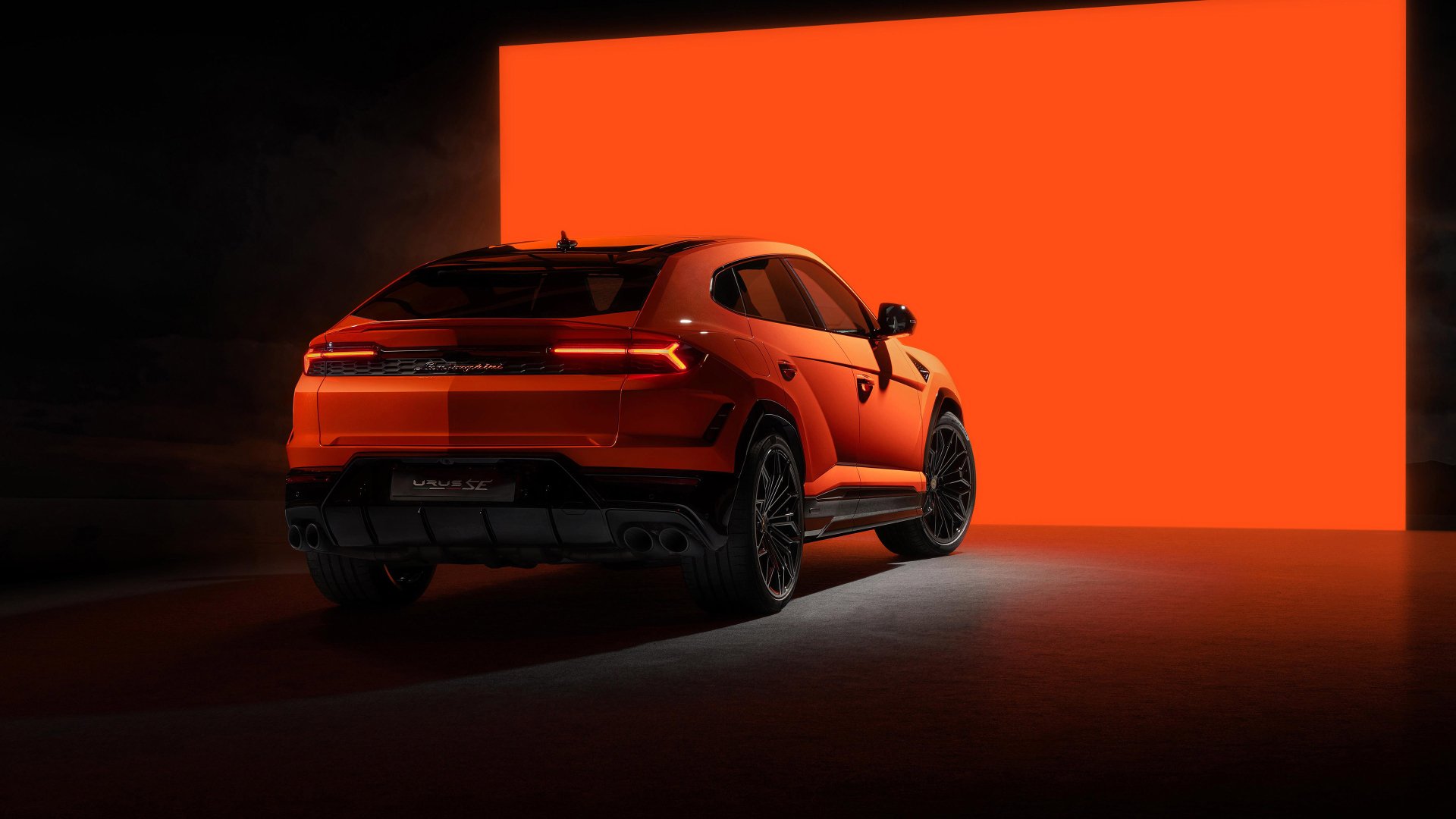HD desktop wallpaper of an orange Lamborghini Urus against a vibrant red background, highlighting the vehicle’s sleek design and sporty appeal.