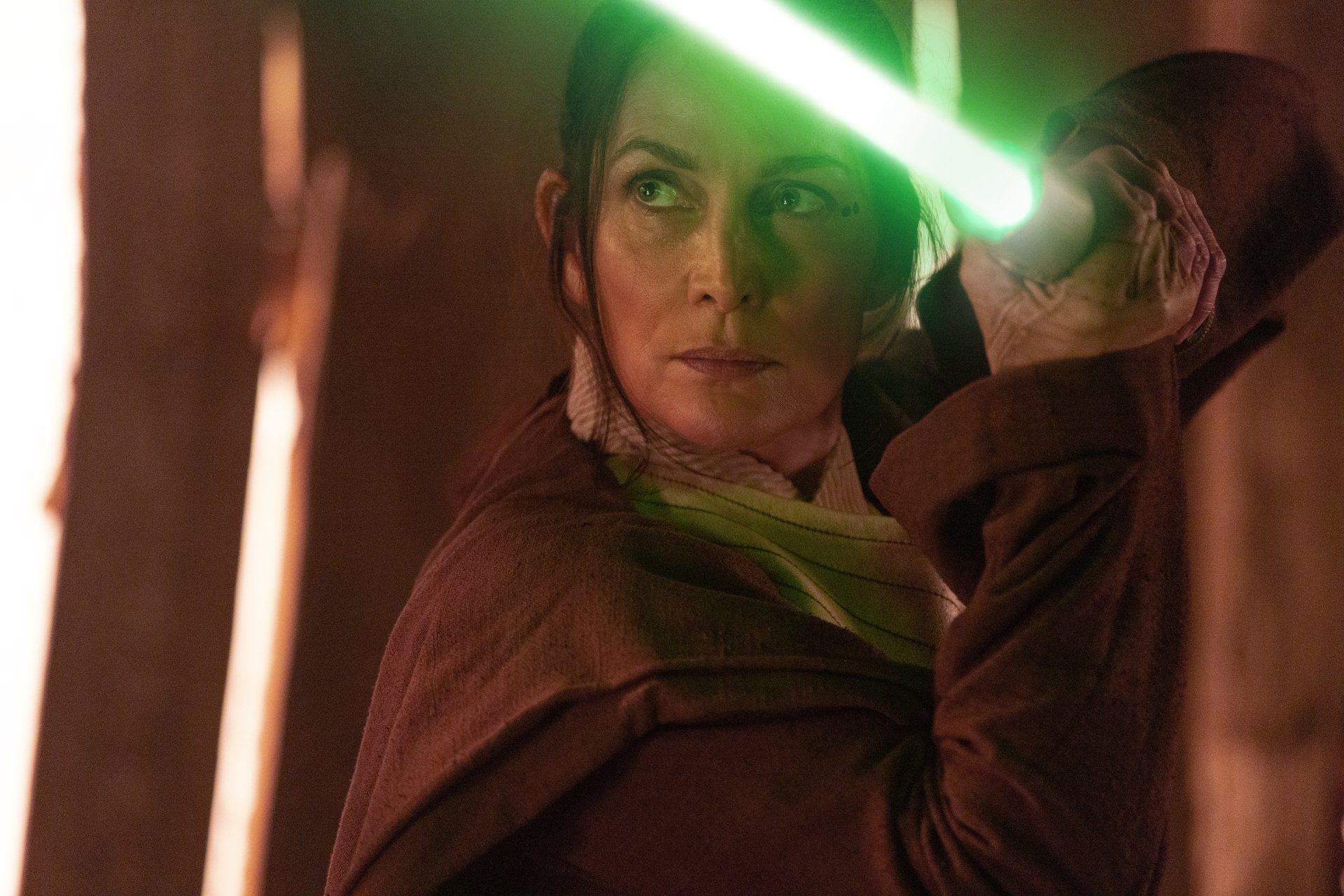 A scene from The Acolyte (2024) TV show featuring a character holding a green lightsaber, captured in an HD desktop wallpaper and background.
