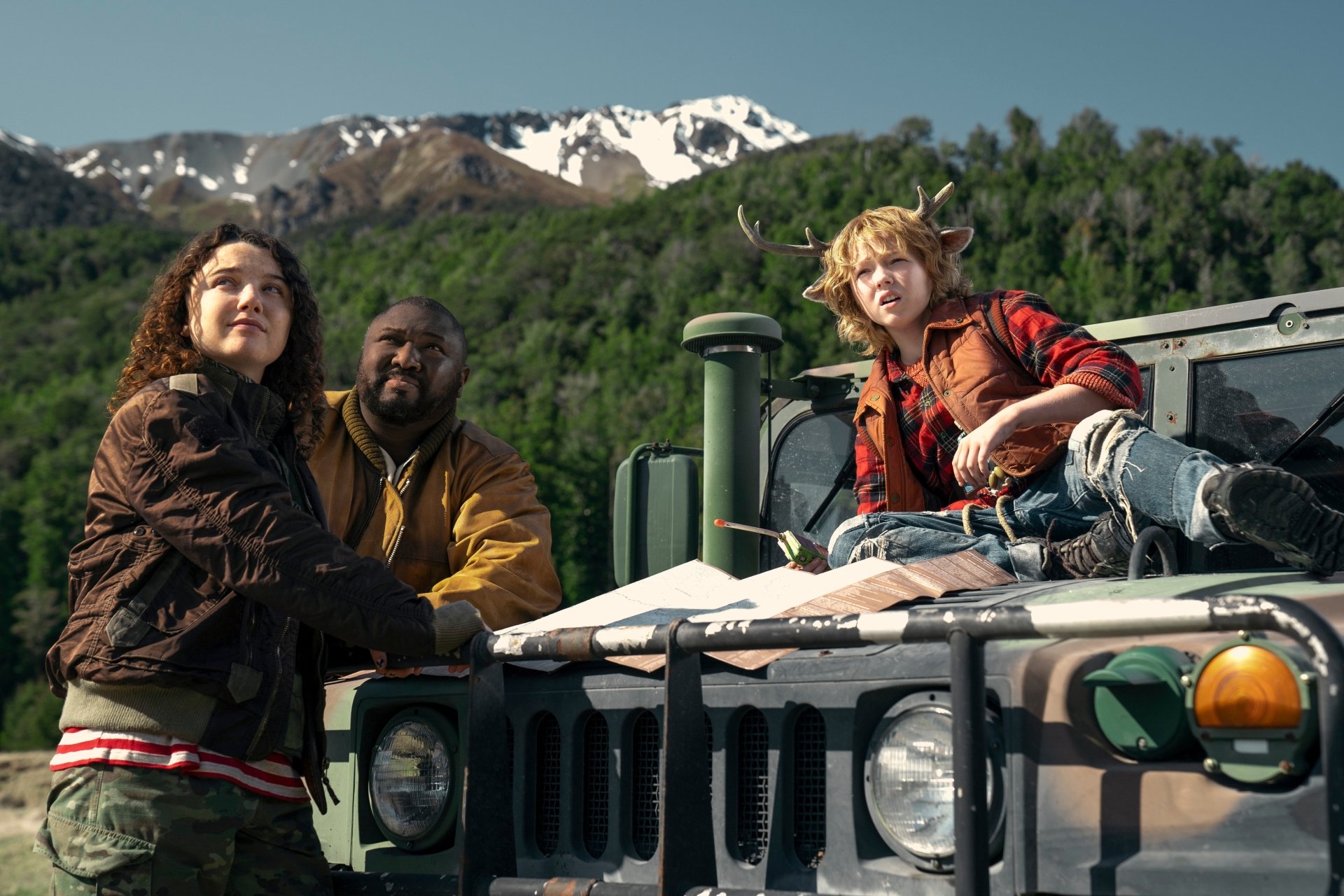 HD wallpaper featuring characters Gus (Christian Convery) and Tommy Jepperd from the TV show 'Sweet Tooth,' with a mountainous landscape in the background, standing beside a vehicle.