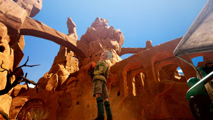 HD desktop wallpaper of Sand Land from a video game, featuring a character standing in a rocky, desert environment under a bright blue sky.