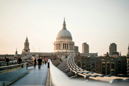 HD desktop wallpaper showing a bridge in London, England, with pedestrians and the iconic dome of St. Paul's Cathedral in the background lit by soft, evening light.