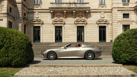 HD desktop wallpaper of a sleek BMW Skytop car parked in front of an elegant, classical building with trimmed bushes on either side.
