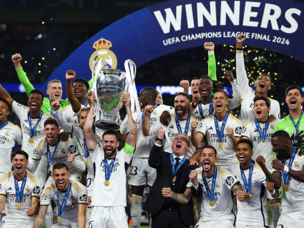 Real Madrid C.F. players celebrating their victory in the 2024 UEFA Champions League final, lifting the trophy amidst jubilant cheers. HD desktop wallpaper and background featuring the winning moment.