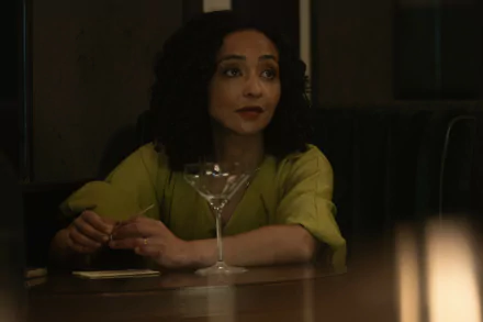 HD desktop wallpaper featuring Ruth Negga from the 2024 TV show Presumed Innocent. Ruth sits at a dim-lit bar with a cocktail glass in front of her, wearing a green blouse and an expression of contemplation.