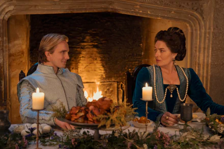 A scene from the movie My Lady Jane featuring two characters in period costumes, sitting at a decorated dinner table with candles, in front of a lit fireplace. HD desktop wallpaper and background.