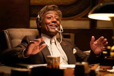 HD desktop wallpaper featuring Giancarlo Esposito in the movie Maxxxine, seated at a desk with a headset, exuding confidence and charisma.
