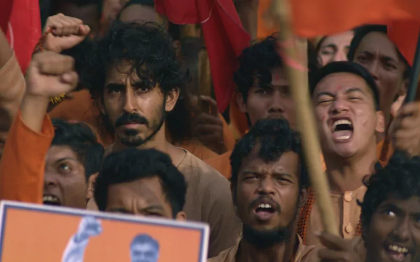 HD desktop wallpaper from the movie Monkey Man (2024), featuring a focused man amidst an exuberant crowd at a rally.