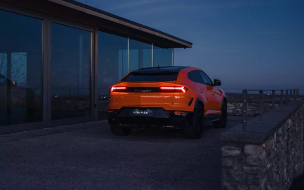 HD desktop wallpaper featuring a Lamborghini Urus parked by a modern house at twilight.
