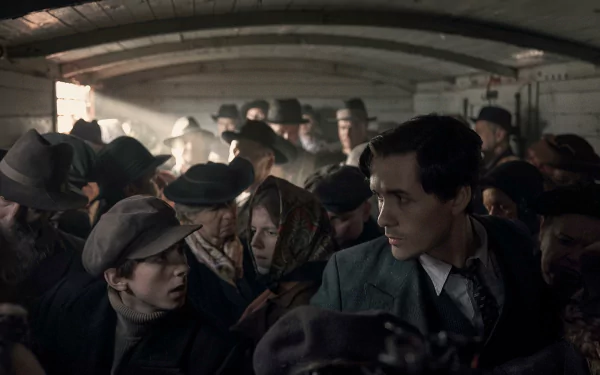 HD desktop wallpaper from the TV show The Tattooist of Auschwitz, depicting a crowded scene with a thoughtful young man looking ahead.