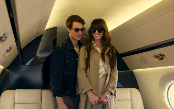 HD desktop wallpaper from the movie The Idea of You, depicting a young man and a woman in sunglasses, holding hands inside a private jet.