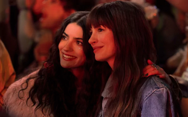 HD desktop wallpaper featuring Anne Hathaway in a scene from the movie The Idea of You, capturing a close and joyful moment with another character at a vibrant event.