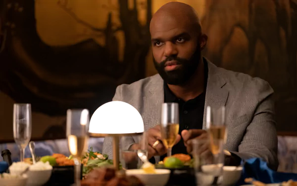 HD desktop wallpaper from the TV show Hacks (2021) featuring a scene with a man dining, gazing intently across a luxuriously set table.