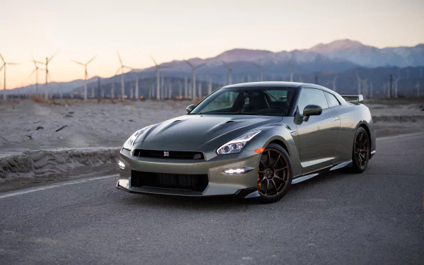 HD desktop wallpaper of a Nissan GT-R parked on a desert road with wind turbines and mountains in the background.