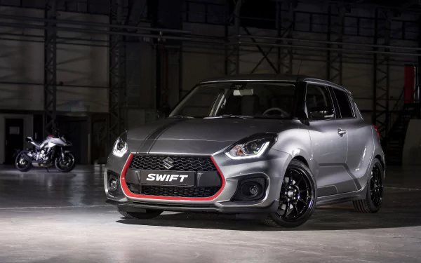 HD desktop wallpaper featuring a Suzuki Swift Sport car in a dimly lit garage, showcasing its sleek design and striking front grille.