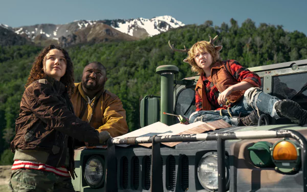 HD wallpaper featuring characters Gus (Christian Convery) and Tommy Jepperd from the TV show 'Sweet Tooth,' with a mountainous landscape in the background, standing beside a vehicle.