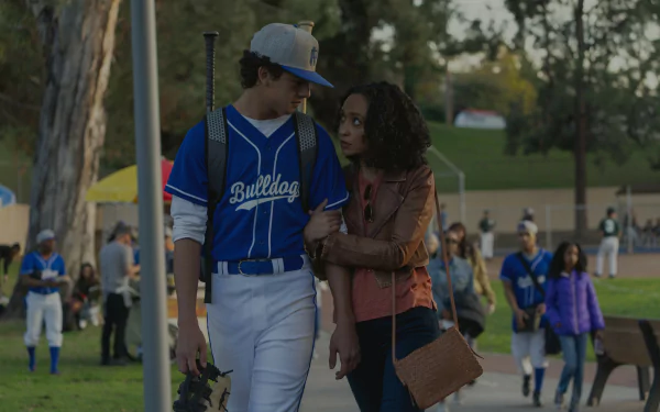 HD desktop wallpaper from the TV show Presumed Innocent (2024), featuring two people, one in a baseball uniform and the other embracing them, with a baseball field and players in the background.