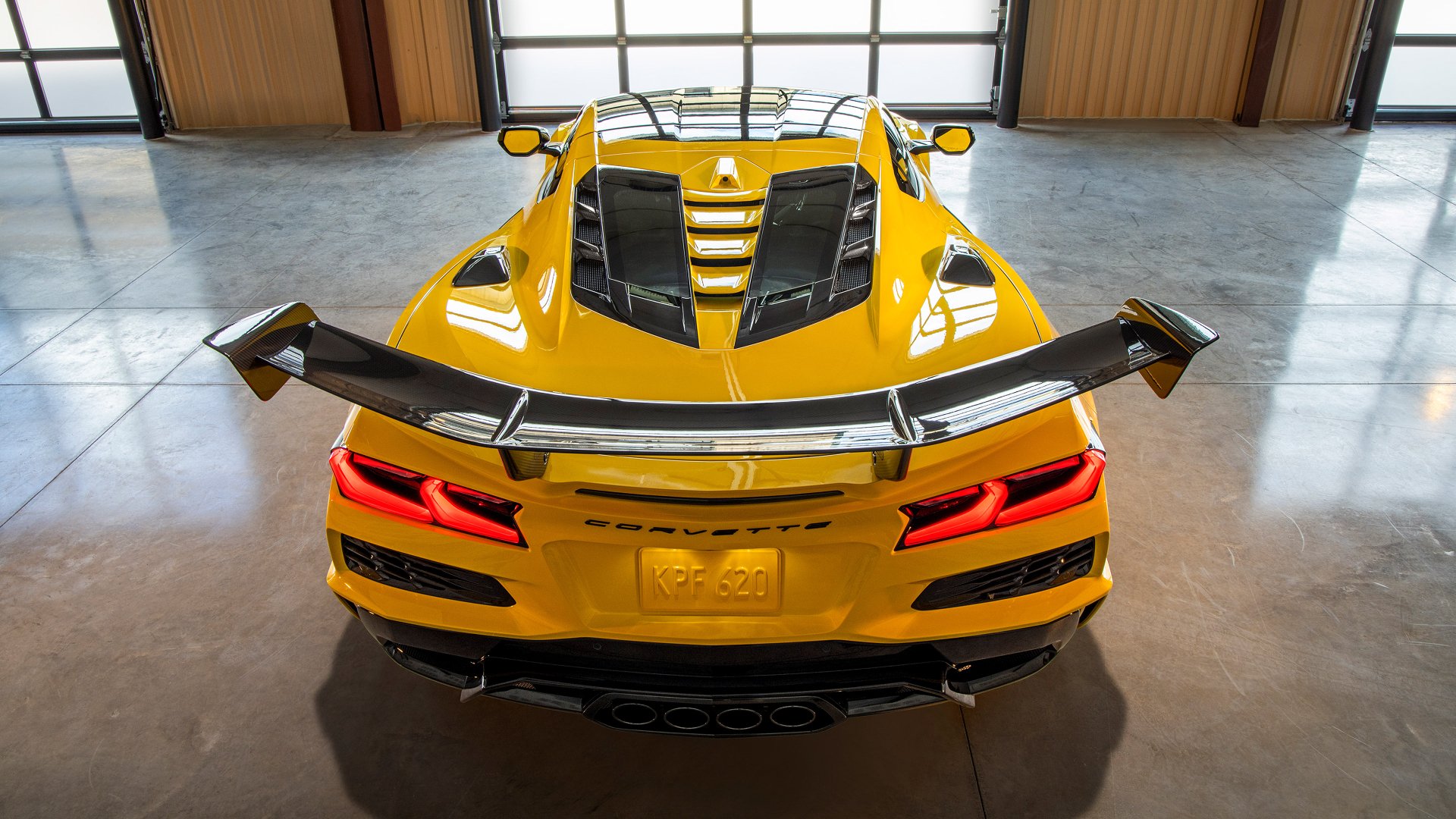 A striking HD wallpaper featuring a yellow Chevrolet Corvette ZR1, showcasing its sleek design and rear spoiler in a modern garage setting.