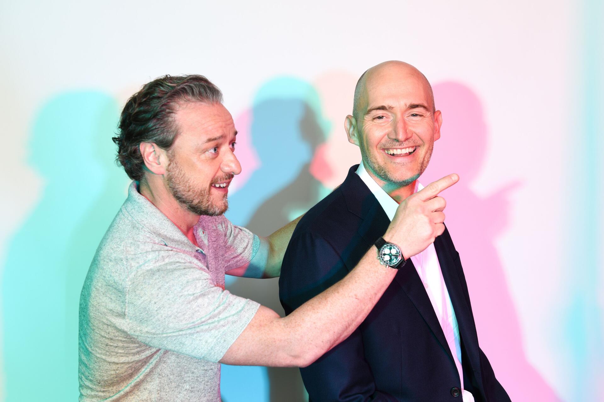 A dynamic promotional image from the movie Speak No Evil, featuring James McAvoy engaging with an actor in a playful interaction against a vibrant backdrop. 