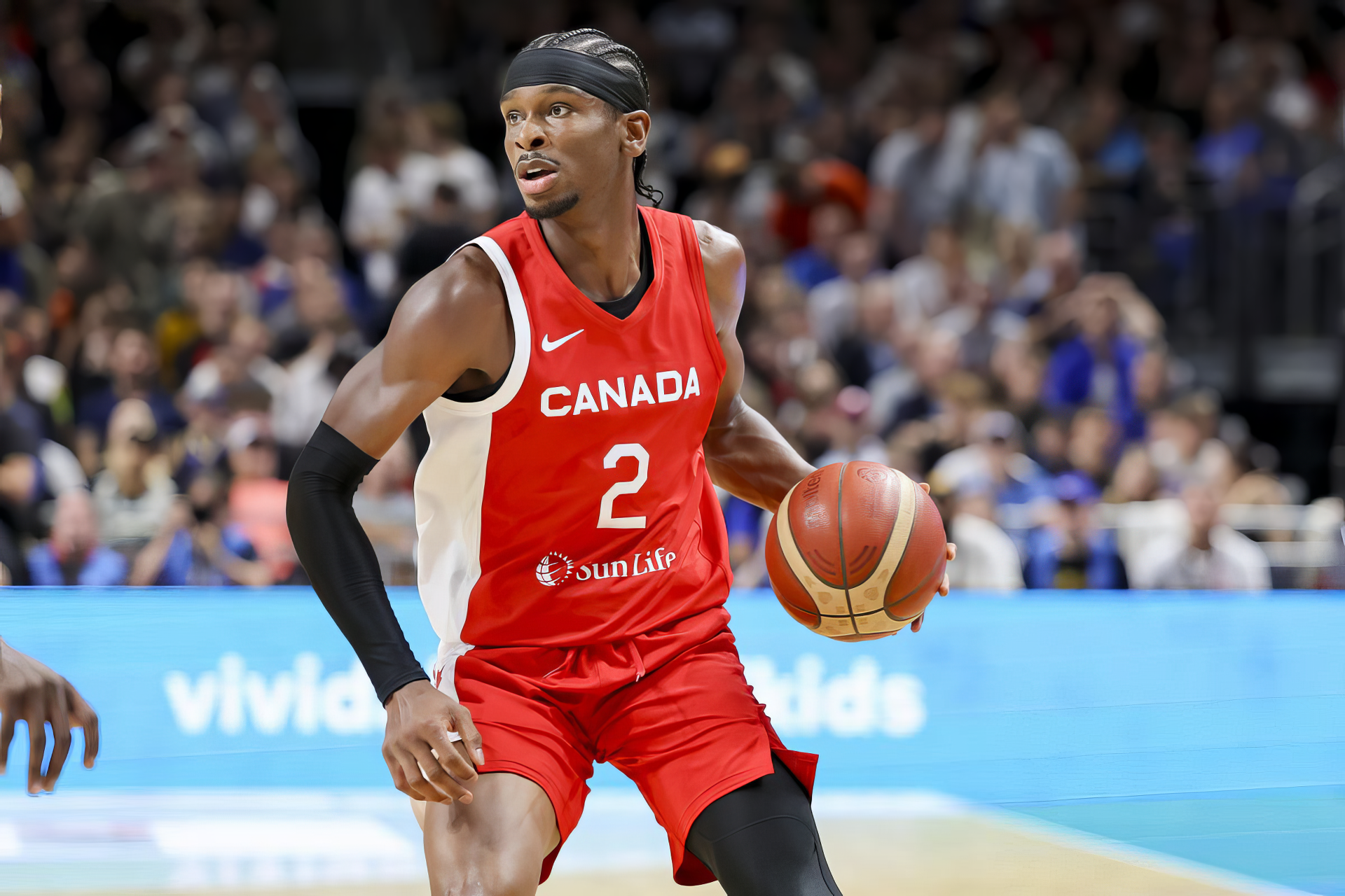 Shai Gilgeous-Alexander dribbles the basketball in a dynamic moment during a game, showcasing Canada's vibrant sports spirit. This HD wallpaper captures the intensity of basketball action.