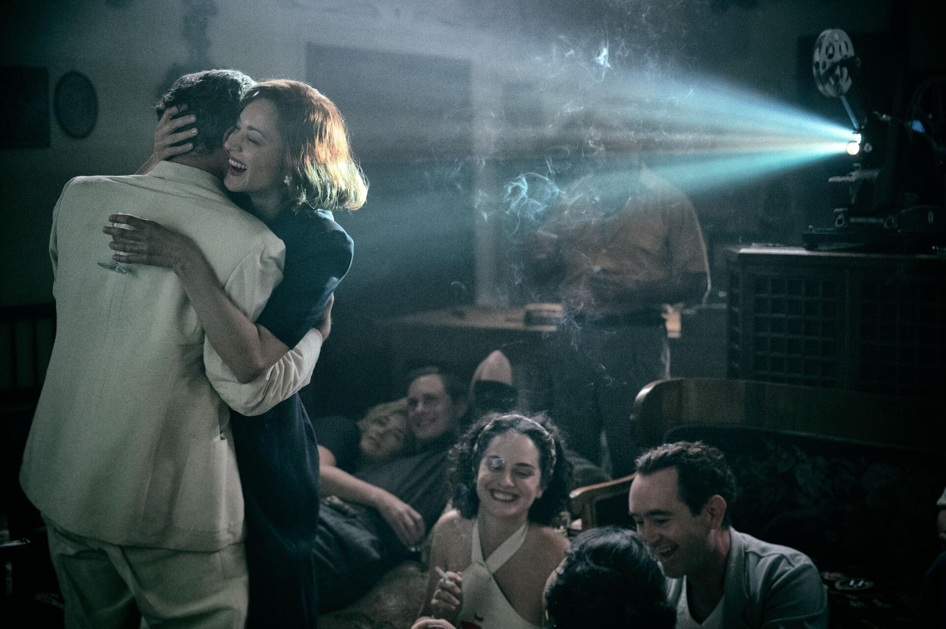 A scene from the movie Lee (2023), featuring a couple dancing in a vintage setting with a film projector and an engaged audience, capturing a nostalgic cinematic moment.