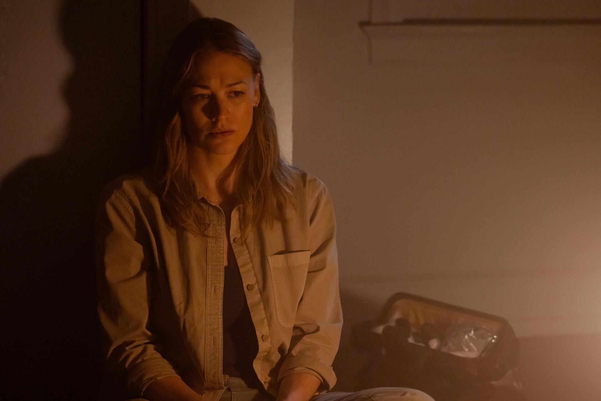 A dramatic scene from the TV show Teacup (2024), featuring Yvonne Strahovski in a dimly lit room, conveying deep emotion and tension. 4K Ultra HD wallpaper for desktop.