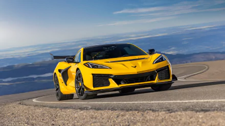 A striking Chevrolet Corvette ZR1 in vibrant yellow, expertly navigating a winding mountain road, captured in stunning detail for an HD desktop wallpaper.