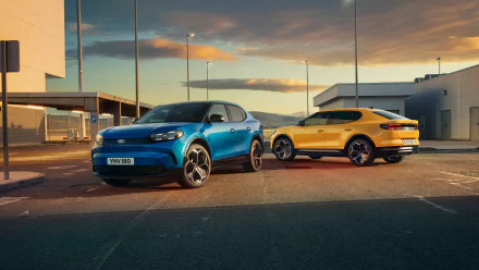 A vibrant HD desktop wallpaper featuring a blue and a yellow Ford Capri parked under a sunset sky, showcasing the stylish design of these iconic cars.