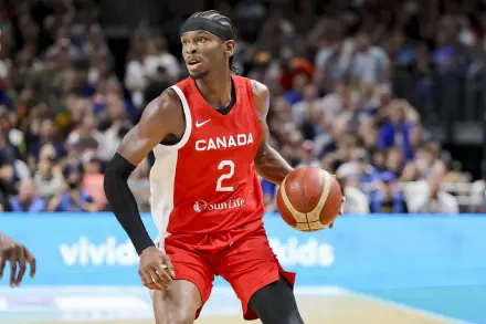 Shai Gilgeous-Alexander dribbles the basketball in a dynamic moment during a game, showcasing Canada's vibrant sports spirit. This HD wallpaper captures the intensity of basketball action.