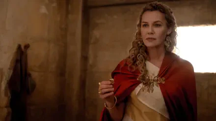 Connie Nielsen as Lucilla in Gladiator II, depicted in a dramatic scene, wearing a flowing gown and a regal red cloak, set against an ancient backdrop. 4K Ultra HD wallpaper.