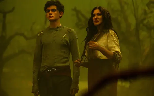 A scene from the TV show Agatha All Along, featuring two characters standing together in a foggy, eerie setting, surrounded by twisted trees and atmospheric lighting. 4K Ultra HD wallpaper.