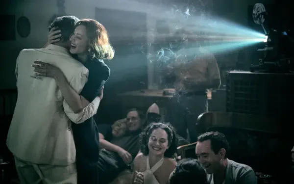 A scene from the movie Lee (2023), featuring a couple dancing in a vintage setting with a film projector and an engaged audience, capturing a nostalgic cinematic moment.