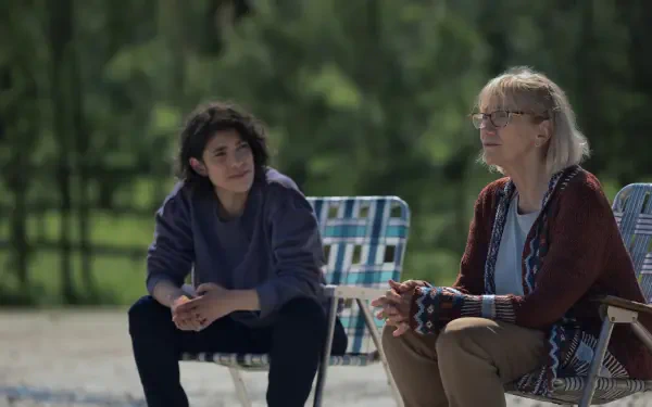 A scene from the TV show Teacup (2024), featuring two characters sitting together in chairs outdoors, engaged in a thoughtful conversation amidst a serene landscape. 8K Ultra HD quality.