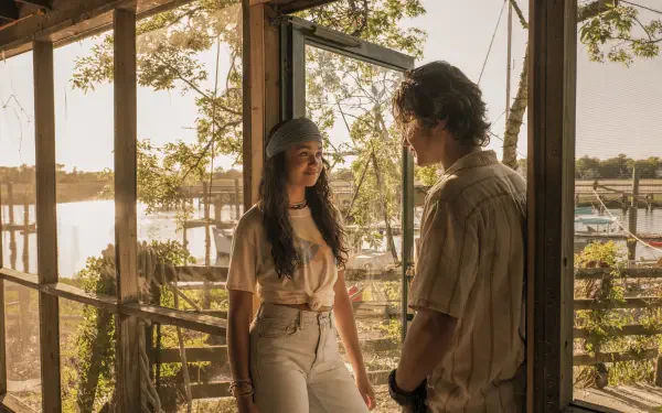 A serene moment from the TV show Outer Banks featuring Madison Bailey and Chase Stokes, set against a backdrop of sunlight and natural scenery.