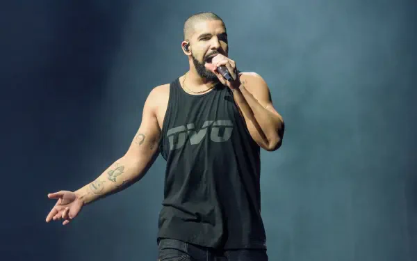 Drake performs passionately on stage, dressed in a black tank top, showcasing his energy as a prominent rapper. This vibrant image serves as a stunning 4K Ultra HD desktop wallpaper.