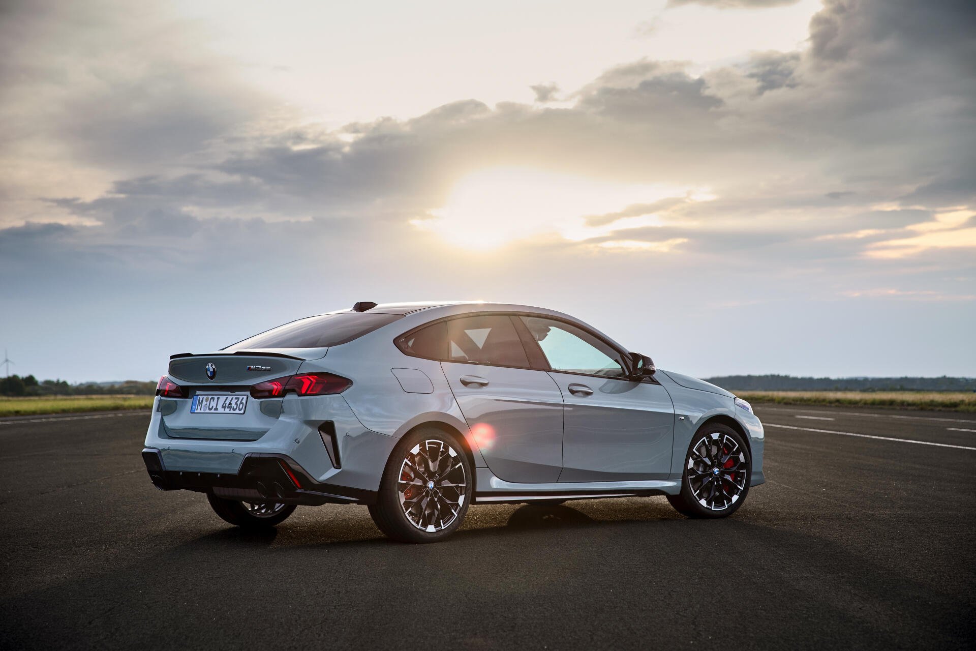 A sleek BMW M235 xDrive Gran Coupe parked on an open road, with a stunning sunset in the background, showcasing its dynamic design and performance features.