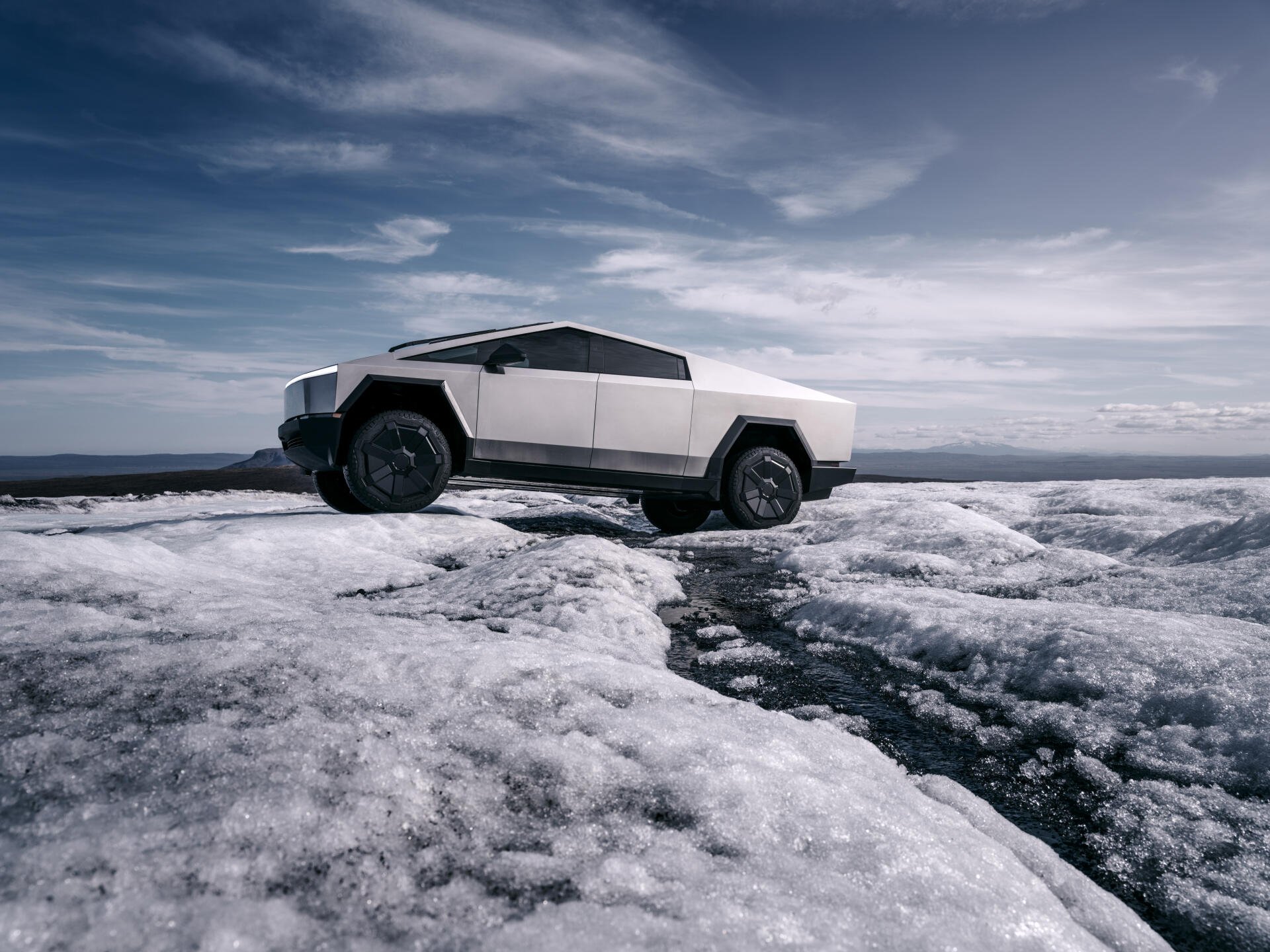 A stunning 4K Ultra HD image of a Tesla Cybertruck positioned on a rugged, icy terrain under a dramatic sky, showcasing its unique design and robust presence.