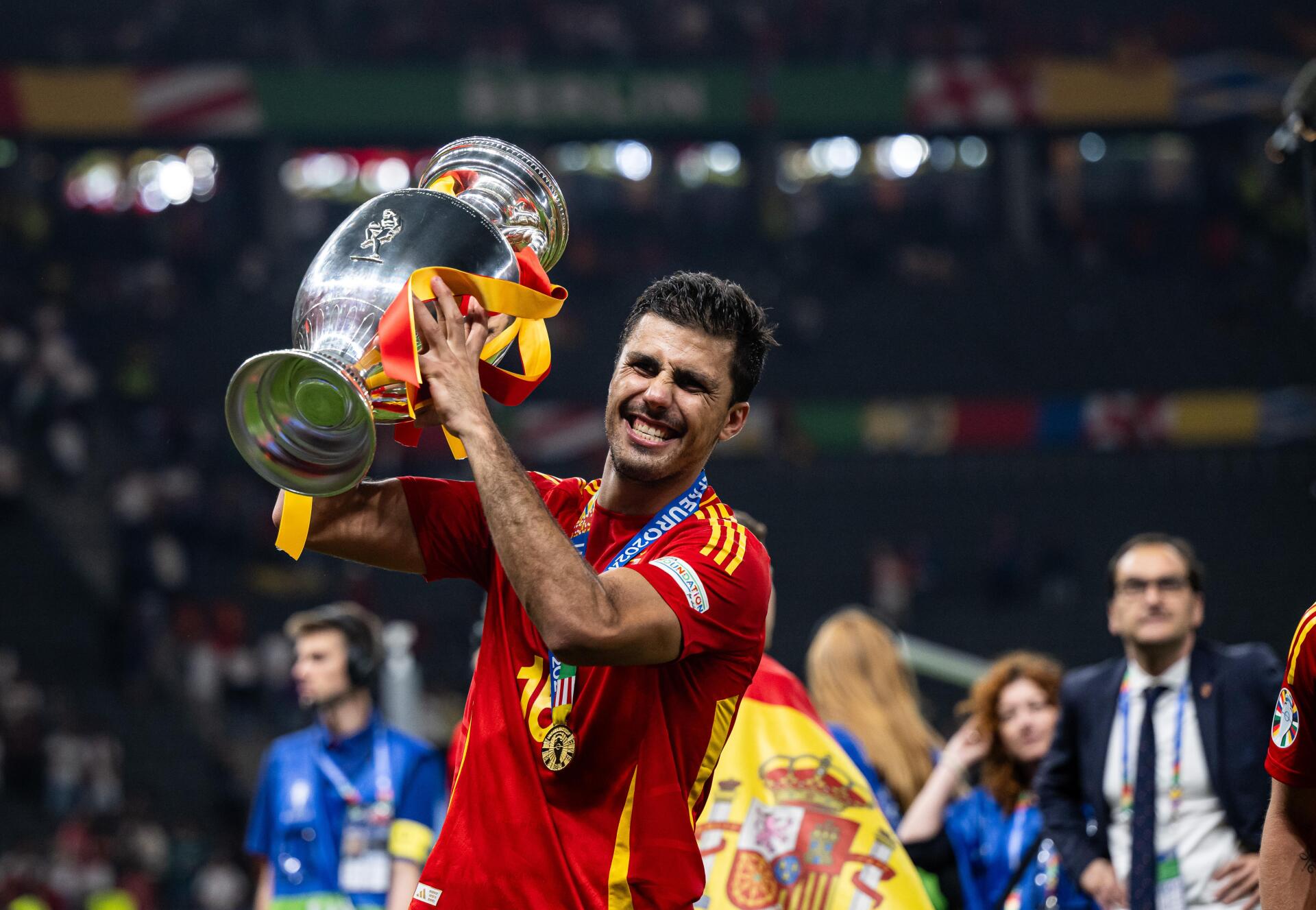 Rodri Hernández celebrates with the trophy after a victory, wearing the Spain National Football Team kit, capturing the joy of the moment in this vibrant 4K Ultra HD wallpaper.