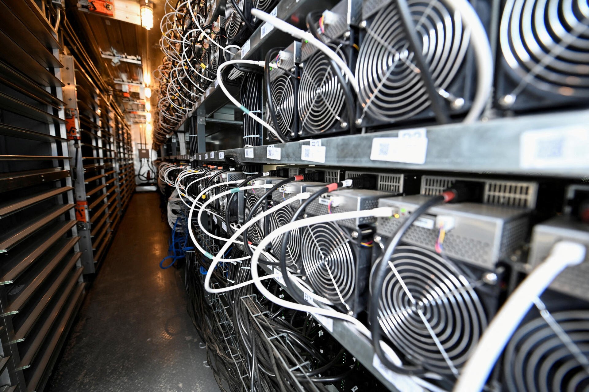 A detailed view of a crypto mining setup, showcasing rows of powerful cooling fans and intricate wiring in a high-tech environment, presented as a 4K Ultra HD desktop wallpaper.
