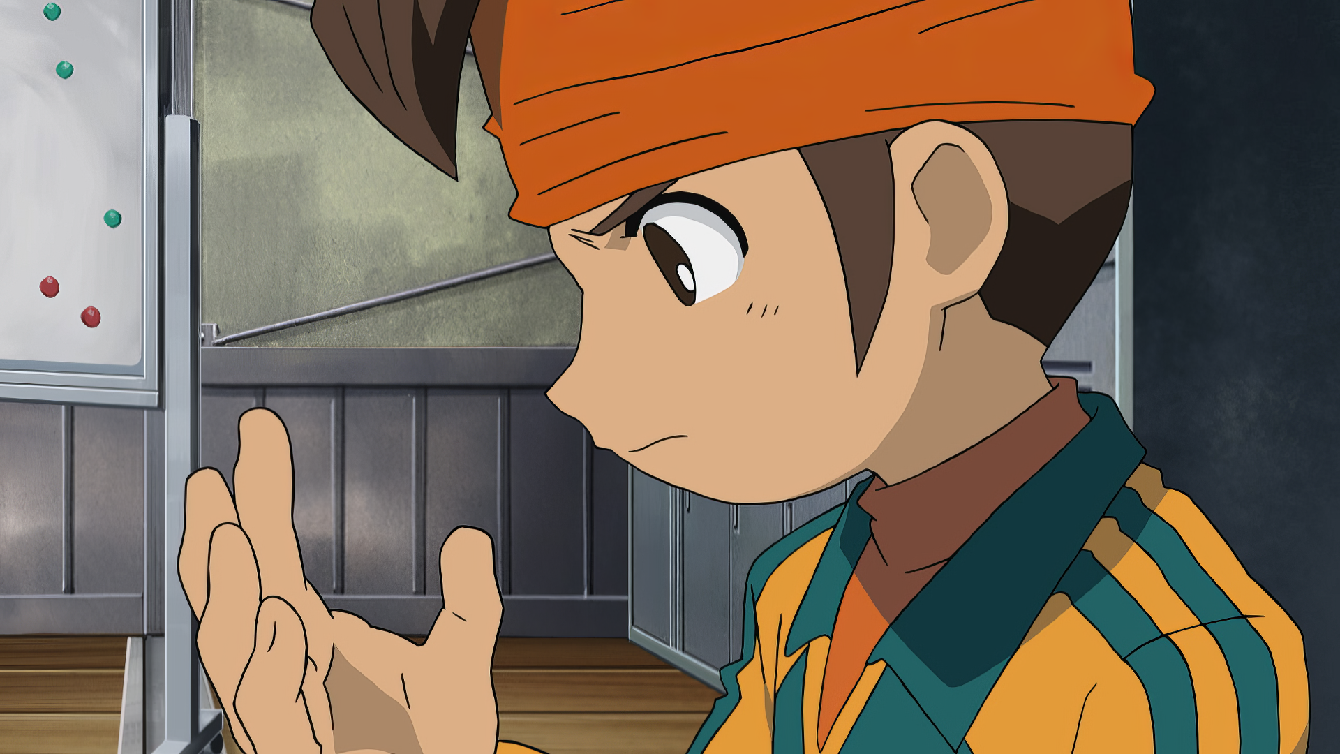 A character from the anime Inazuma Eleven, shown with an orange headband and striped jacket, gazes thoughtfully at his hand, set against a classroom background. HD PC wallpaper.