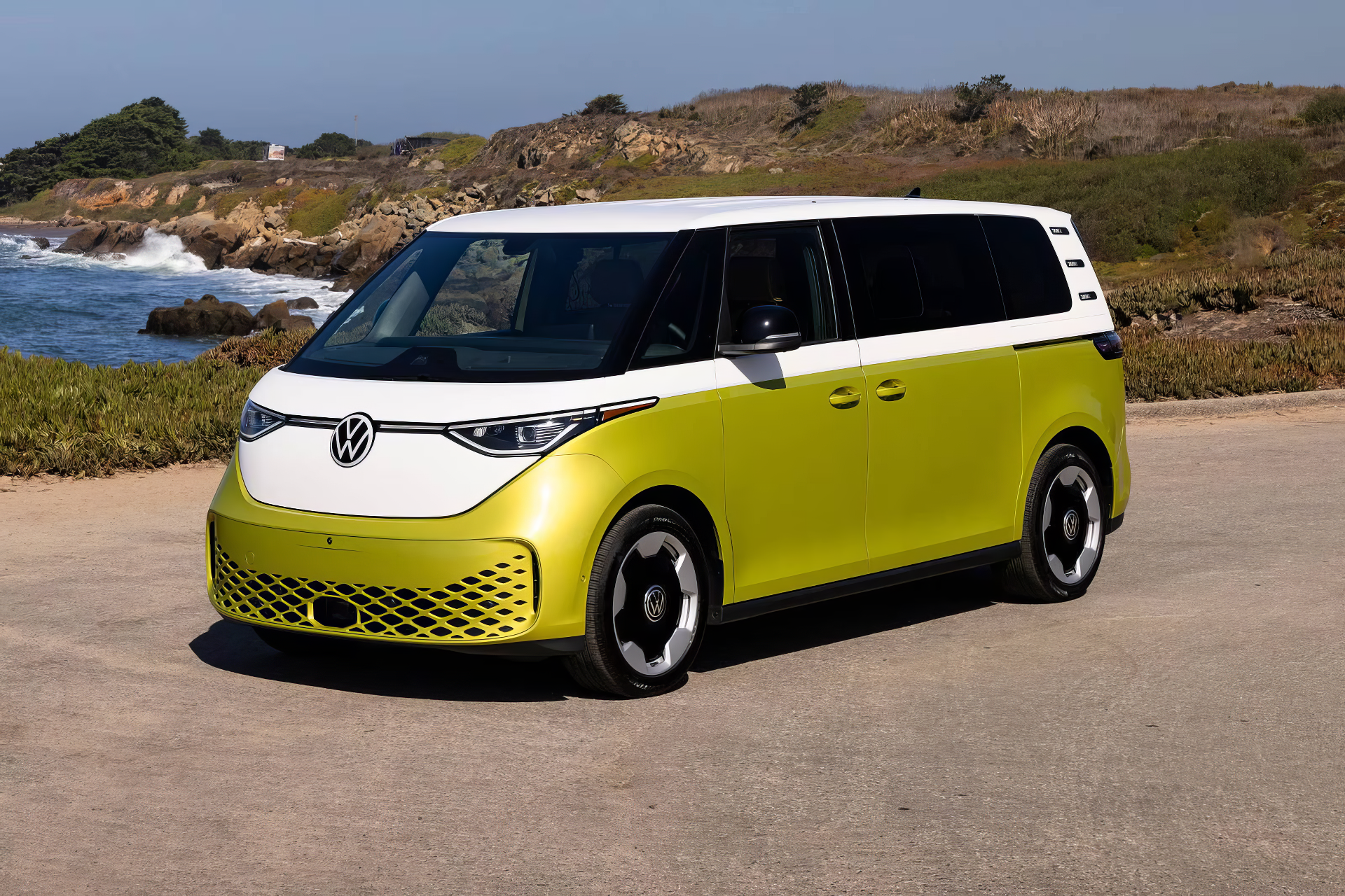 A vibrant Volkswagen ID. Buzz electric car parked by the coast, showcasing its distinctive design with a bright green and white color scheme against a scenic backdrop.