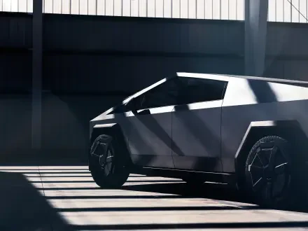 A sleek Tesla Cybertruck showcased in a dramatic, shadowed setting, highlighting its futuristic design. This image serves as a striking 4K Ultra HD desktop wallpaper.