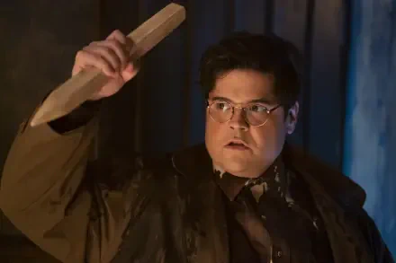 Harvey Guillén in a dramatic scene from the TV show What We Do in the Shadows, holding a wooden object, captured in a high-definition desktop wallpaper.