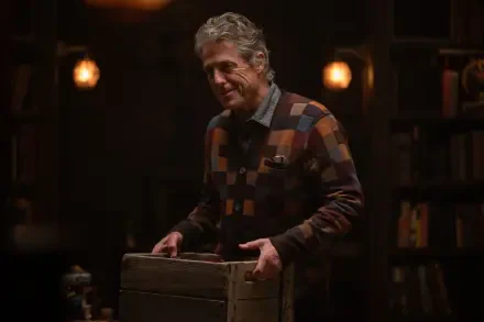 A scene from the movie Heretic (2024) featuring Hugh Grant, showcasing a warm, atmospheric setting with dim lighting and a wooden crate. 4K Ultra HD wallpaper.