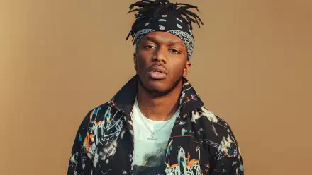 High-definition desktop wallpaper featuring KSI, showcasing him in a stylish outfit with a bandana against a warm beige background.