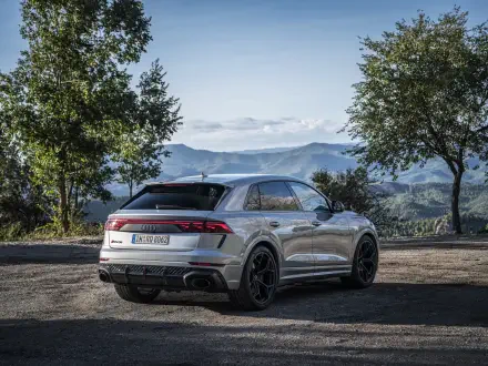 A sleek Audi RS Q8 parked in a scenic landscape, showcasing its modern design against a backdrop of mountains and trees, captured in 4K Ultra HD quality.
