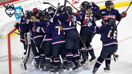 A dynamic UConn Athletics image showcases the excitement of a hockey team celebrating together on the ice, capturing the spirit of sports in a vibrant HD desktop wallpaper.