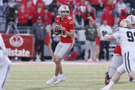 A dynamic moment of an Ohio State Buckeyes football player in action, preparing to throw the ball, set against a vibrant game-day atmosphere. HD desktop wallpaper for sports enthusiasts.