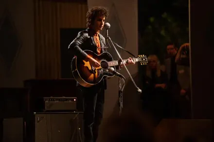 Timothée Chalamet performs with a guitar in a scene from the movie A Complete Unknown. The high-resolution image captures the dynamic atmosphere of the performance.