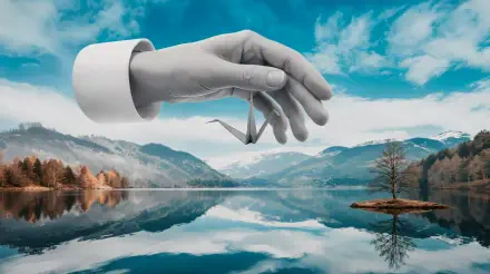 A serene landscape features a hand delicately holding a small origami crane above a tranquil lake, with mountains and a clear blue sky reflected in the water. 4K Ultra HD wallpaper.